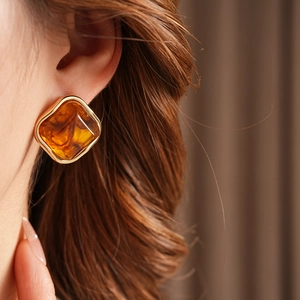 Close-up of vintage geometric amber gemstone earrings set in a gold-tone metallic frame