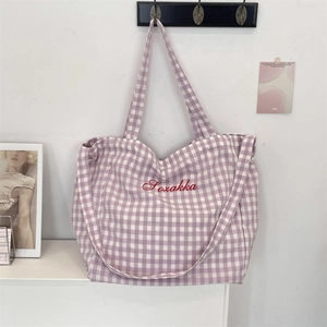 Detail of purple checkered tote bag with Sozakka embroidery hanging on a white wall