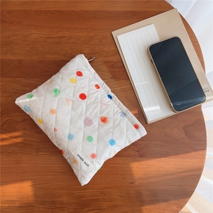 Close-up of quilted cotton makeup bag with colorful polka dots on a wooden table