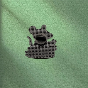 Detail view of the back of a metal cartoon mouse brooch with a black rubber clutch pin back