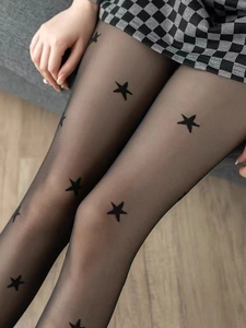 Detail of sheer black tights featuring a star print pattern with a plaid skirt