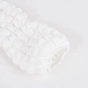 Detailed macro view of white textured bubble fabric and elastic cuff on the long sleeve