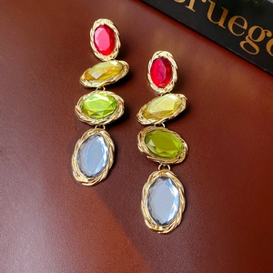 Macro detail of vintage gold-rimmed earrings with four colorful oval gemstones