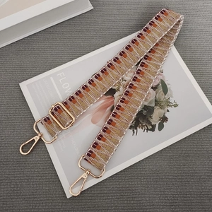 Close-up of woven bag strap with geometric patterns and golden metal swivel hooks