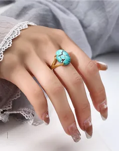 Detailed view of an oval turquoise ring set in a gold four-prong V-shaped band on finger