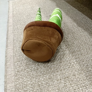 Détail de la peluche en forme de pot de fleur avec base brune et feuilles vertes douces