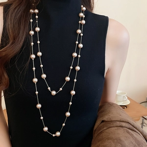 Detail of elegant double-layered champagne pearl necklace on a black turtleneck sweater
