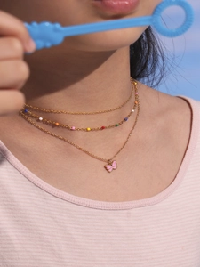 Close-up of double layer gold necklace with pink butterfly pendant and colorful beads