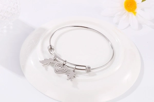 Adjustable silver steel bracelet with heart, boy, and girl charms on ceramic