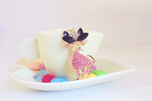 Close-up of golden cat keychain with pink rhinestones on a white heart tray