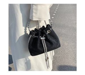 Detail of a mini black bucket bag with sparkling rhinestones and silver metal ring handle