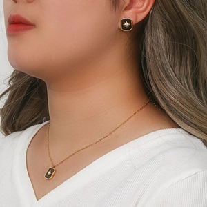 Detail of model wearing a gold starburst necklace and matching square stud earrings