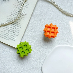 Dettaglio dei supporti per telefono a forma di waffle verde e arancione su superficie bianca