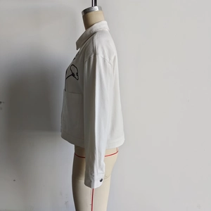 Detail of white embroidered twill jacket featuring minimalist black line art on the front