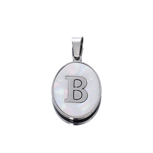 Detailed macro view of oval stainless steel pendant with letter B on white mother of pearl