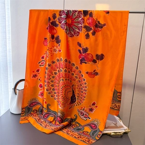 Nahaufnahme eines eleganten orangefarbenen Seidenschals mit Pfauenmuster an einer Tasche