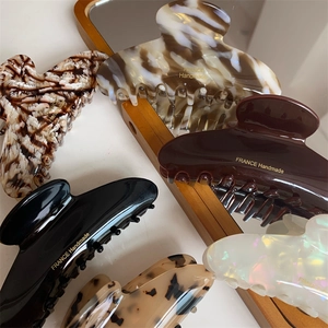 Close-up of handmade acetate hair claws in various marble colors with gold lettering