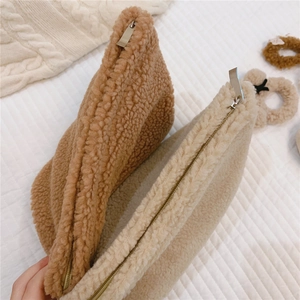 Detailed texture of plush fleece makeup bags in brown and white with zip closure