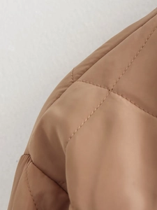 Macro shot of brown quilted bomber jacket fabric showing detailed stitching and nylon texture