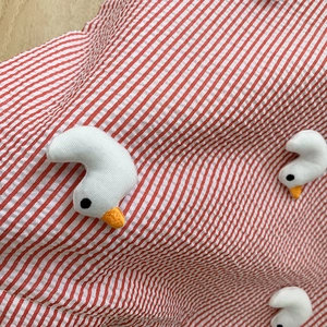 Macro detail of red striped seersucker fabric with cute 3D duckling patch embroidery