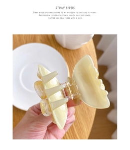 Detailed view of a creamy yellow camellia hair claw clip with elegant shell texture