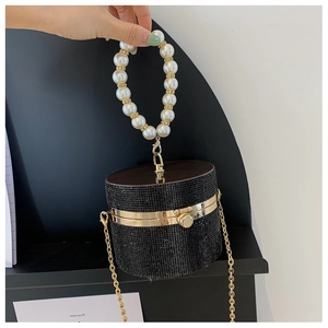 Detail view of black rhinestone cylinder evening bag with pearl ring handle and gold chain strap