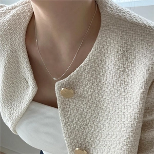 Close-up of minimalist silver pearl necklace on model in elegant tweed jacket