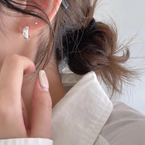 Close-up of 925 sterling silver hoop earrings with quilted texture on earlobe