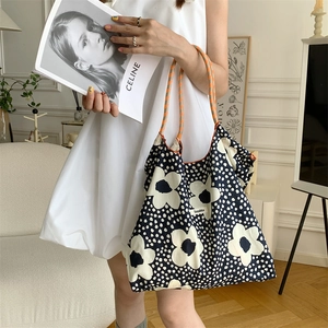 Shoulder tote bag with daisy print and woven handles shown in a lifestyle setting