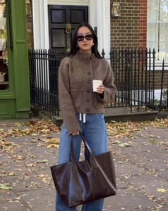 Photo en extérieur d'un gilet en maille marron avec cabas en cuir et jean large