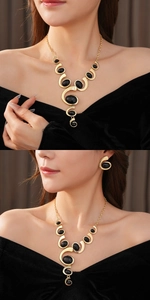 Detailed view of model wearing a vintage gold necklace and earring set with black oval stones