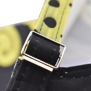 Macro shot of adjustable silver buckle and yellow polka dot webbing on canvas baseball cap