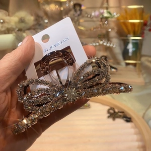 Detail view of large rhinestone bow hair claw clip with golden finish and star accent