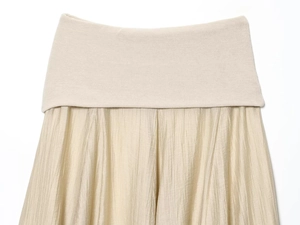 Detail des cremefarbenen Plisseerocks mit Strickbund und Chiffon-Stoffstruktur