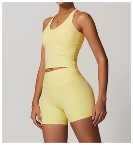 Detail of cross-back yoga top and high-waisted shorts in yellow for fitness