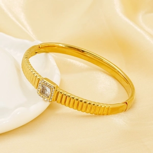Luxurious gold plated ribbed bangle featuring a square zircon center on white shell plate