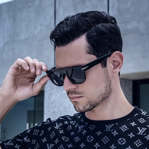 Close-up of black oversized sunglasses with silver arrow hinge detail on model