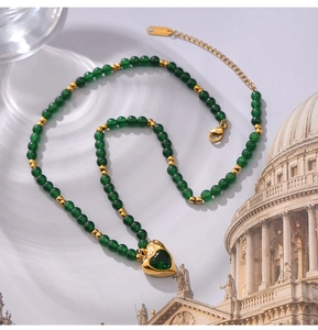 Détail du collier de perles vertes avec pendentif cœur doré et zircon sur fond rétro chic
