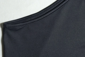 Macro shot of double-needle stitching on high-stretch black knit dress fabric texture
