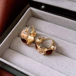 Detailed shot of retro gold ear clips with champagne diamonds and brown resin