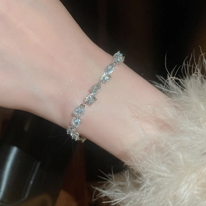 Close-up of model wearing light blue zircon oval gemstone bracelet with silver claw setting