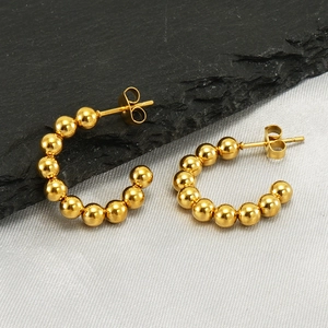 Elegant gold stainless steel beaded C-shaped hoop earrings for women on silk background