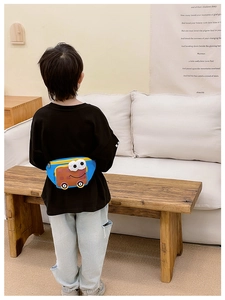Rear view of a child wearing the blue cartoon bus crossbody bag in a cozy indoor setting
