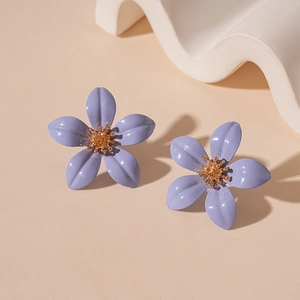 Close-up of purple five-petal flower earrings with golden center on decorative stand