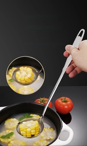 Detail eines tiefen Edelstahl-Suppenlöffels mit langem Griff beim Schöpfen von Mais