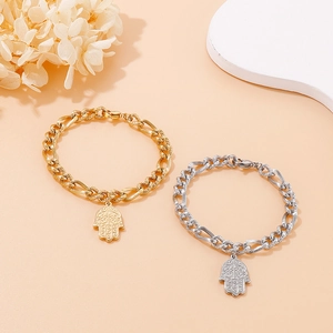Bracciali con mano di Fatima in acciaio inossidabile oro e argento su sfondo beige
