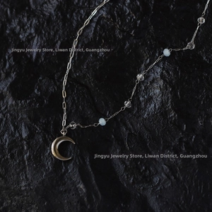 Close-up of crescent moon pendant with clear crystal beads on a titanium steel chain