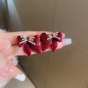 Dettaglio di eleganti orecchini a fiocco in velluto rosso con strass scintillanti incastonati