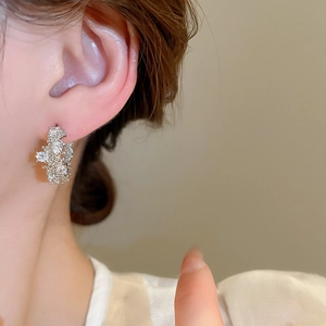 Macro close-up of a silver zircon earring with irregular cluster design on a female model