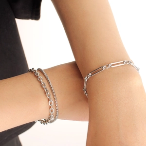 Detail of silver stainless steel double layer twist and paperclip chain bracelets on wrist